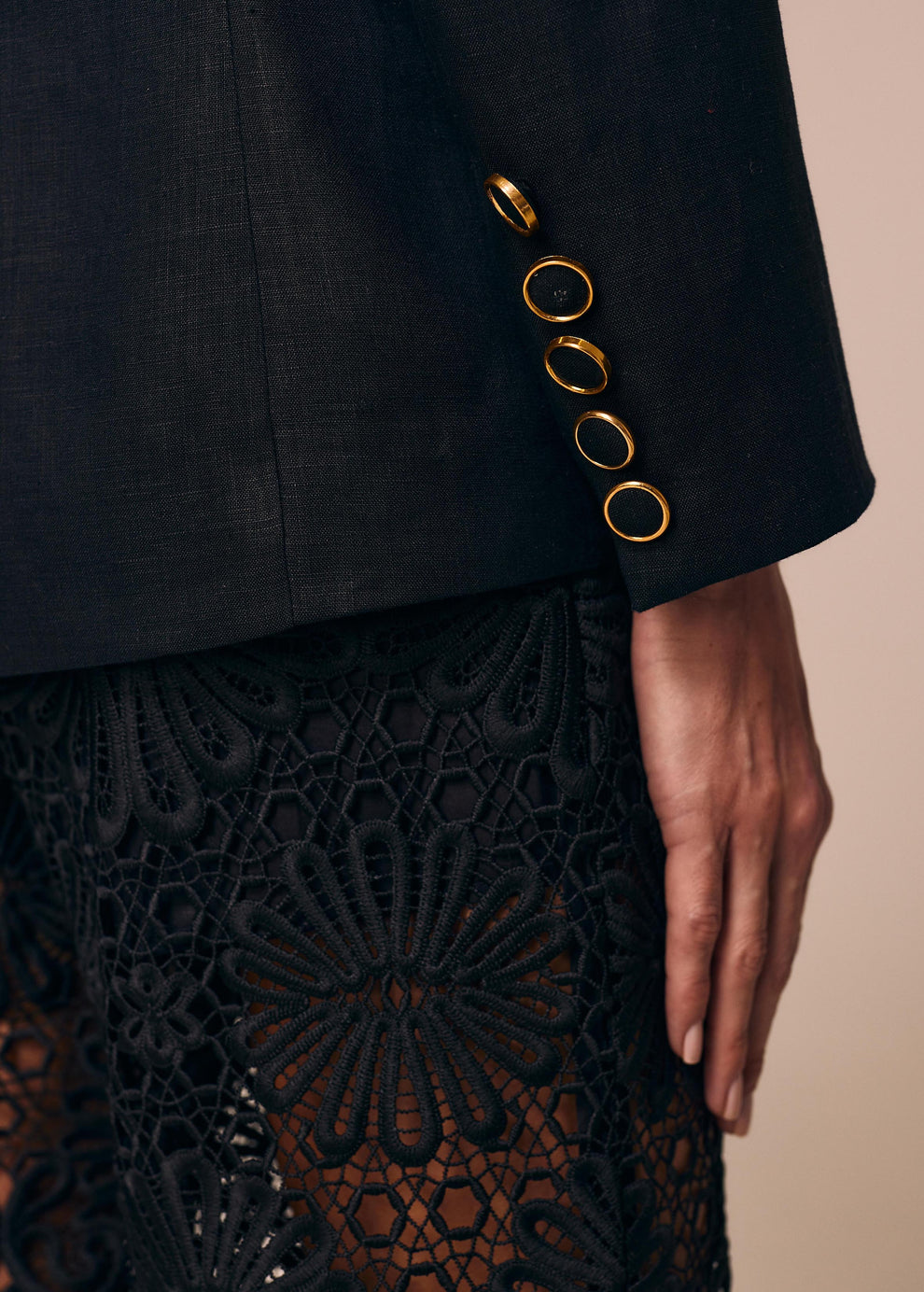 Detalhe do punho do blazer de alfaiataria Essêcia La Gea preto com botão forrado e detalhe dourado 