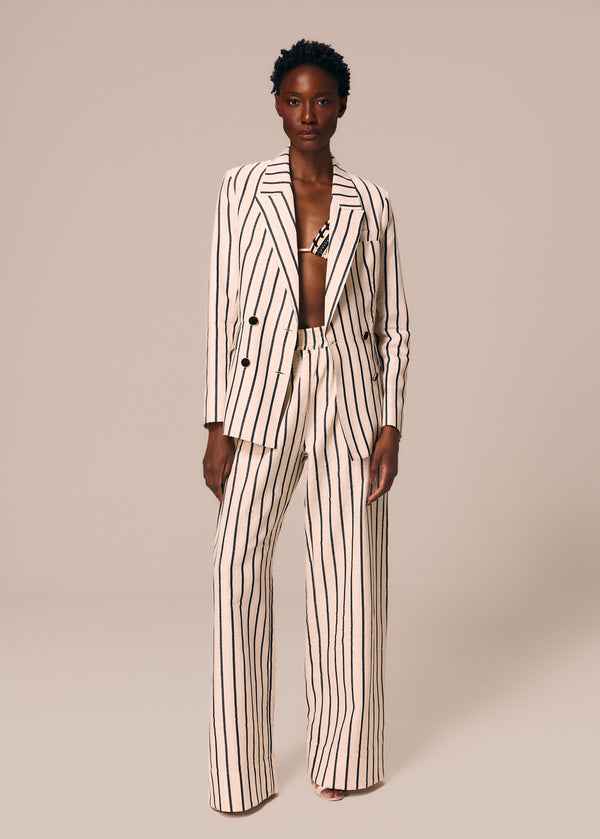 Modelo veste blazer e calça reta listrado Eterno e top de biquíni cortininha Calor La Gea