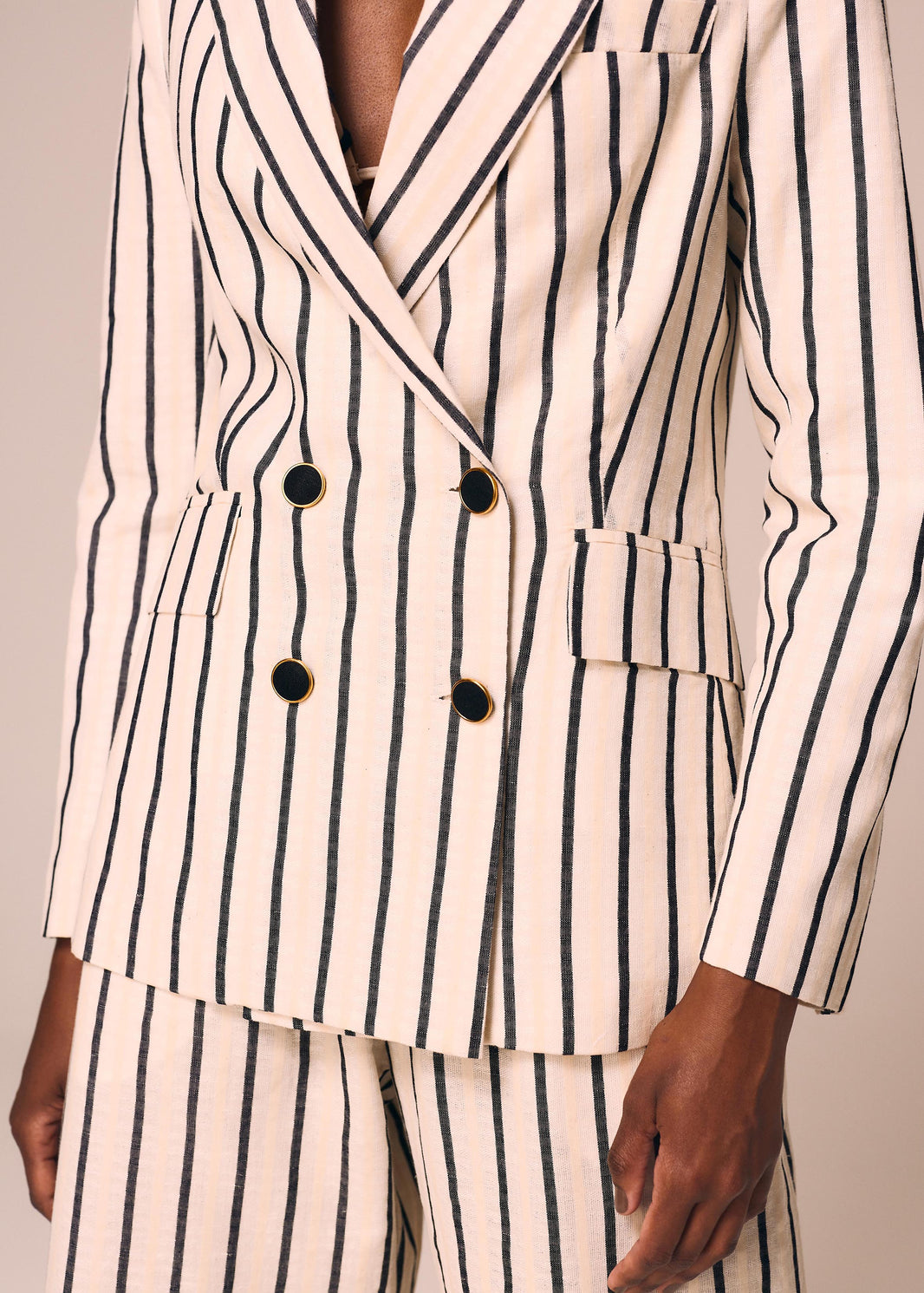 Detalhe do blazer listrado off White e preto Eterno La Gea com abotoamento duplo