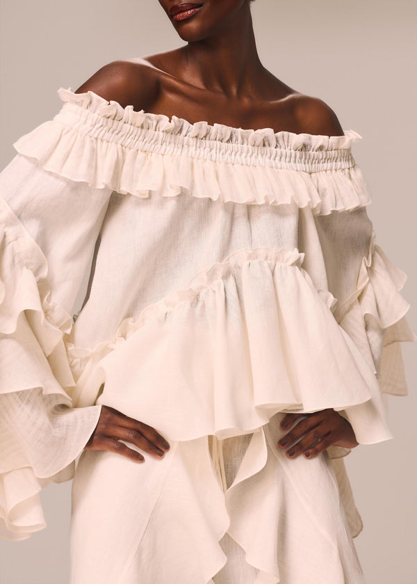 Detalhe da modelo com a blusa ombro a ombro Etéreo La Gea na cor off White com babados nas mangas e na barra