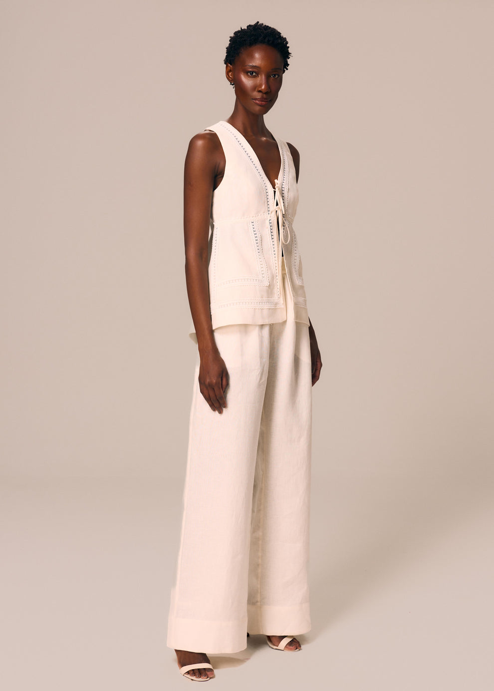 Modelo veste calça boxer off White Essência La Gea e blusa regata com amarração dupla frontal