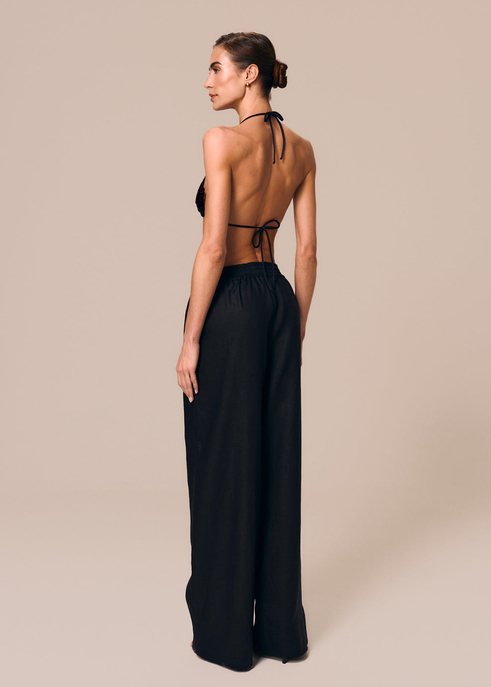 Modelo de costas veste calça boxer preta Essência com top de biquíni cortininha Pedra La Gea