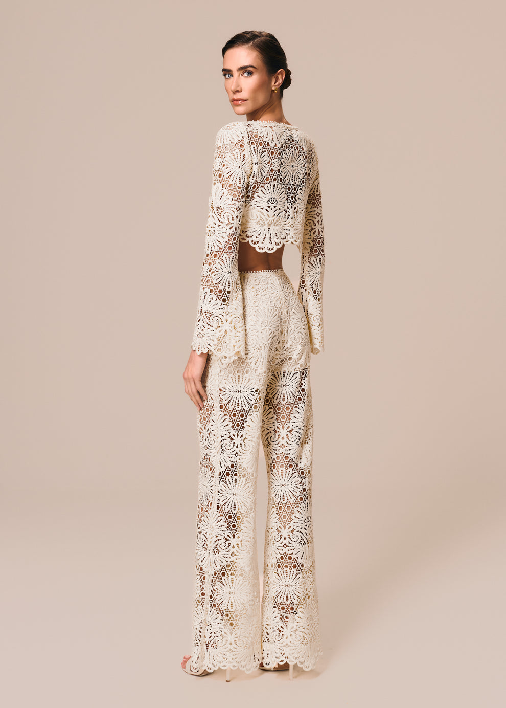 Modelo veste composição em renda off White com calça flare e top cropped manga longa Cerâmica La Gea