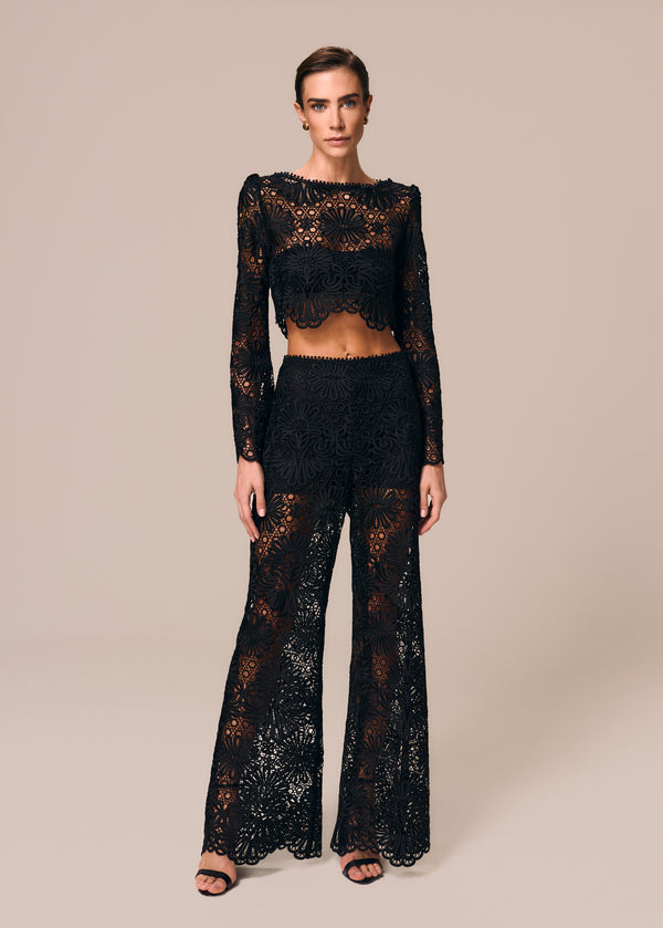 Modelo combina calça flare em renda preta com top cropped manga longa Cerâmica La Gea