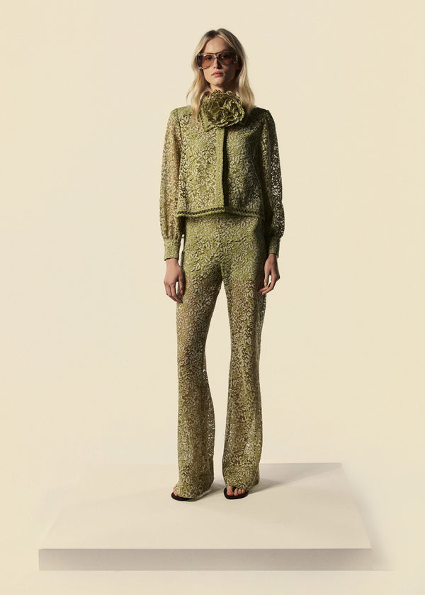 Modelo combina calça flare de renda com camisa feminina e cinto utilizado como colar de flores. Peças da família Bosque da La Gea.