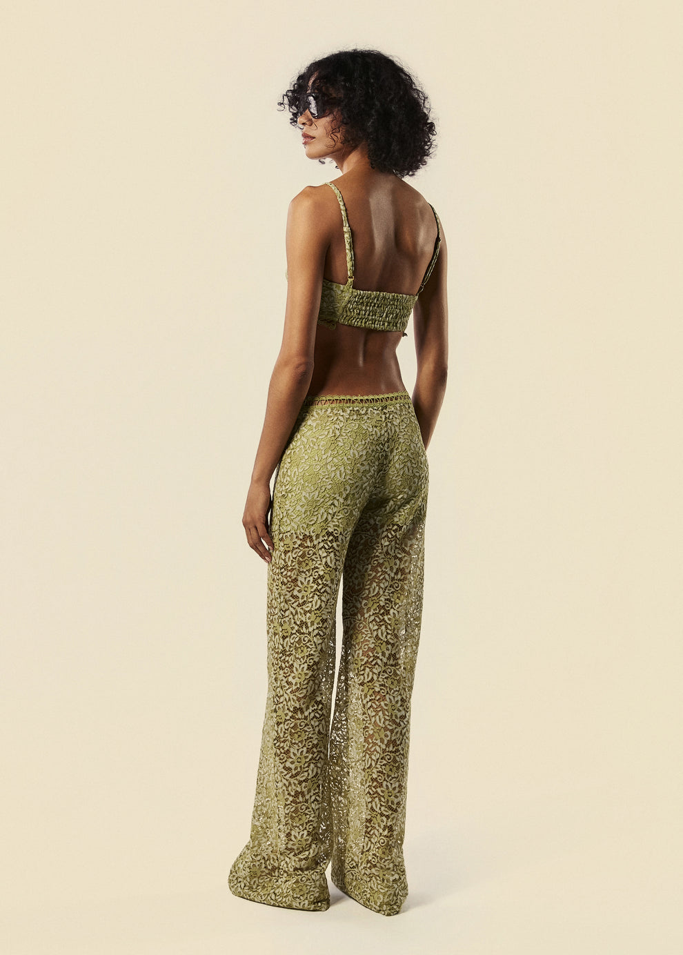 Modelo de costas com a calça flare de renda Bosque com top da mesma coleção de Verão 27 da La Gea.
