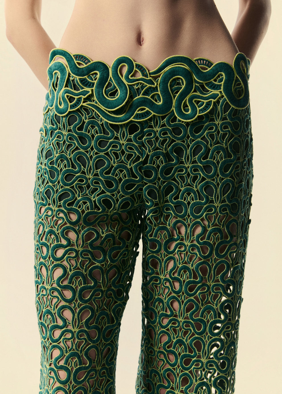 Detalhe do cós da calça flare Trilhas da La Gea com detalhes em renda com serpentes esverdeadas. 