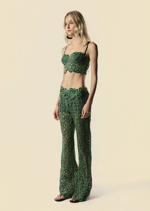 Modelo usa calça flare verde de renda com serpentes e top corset do lançamento de Verão 27 da La Gea.