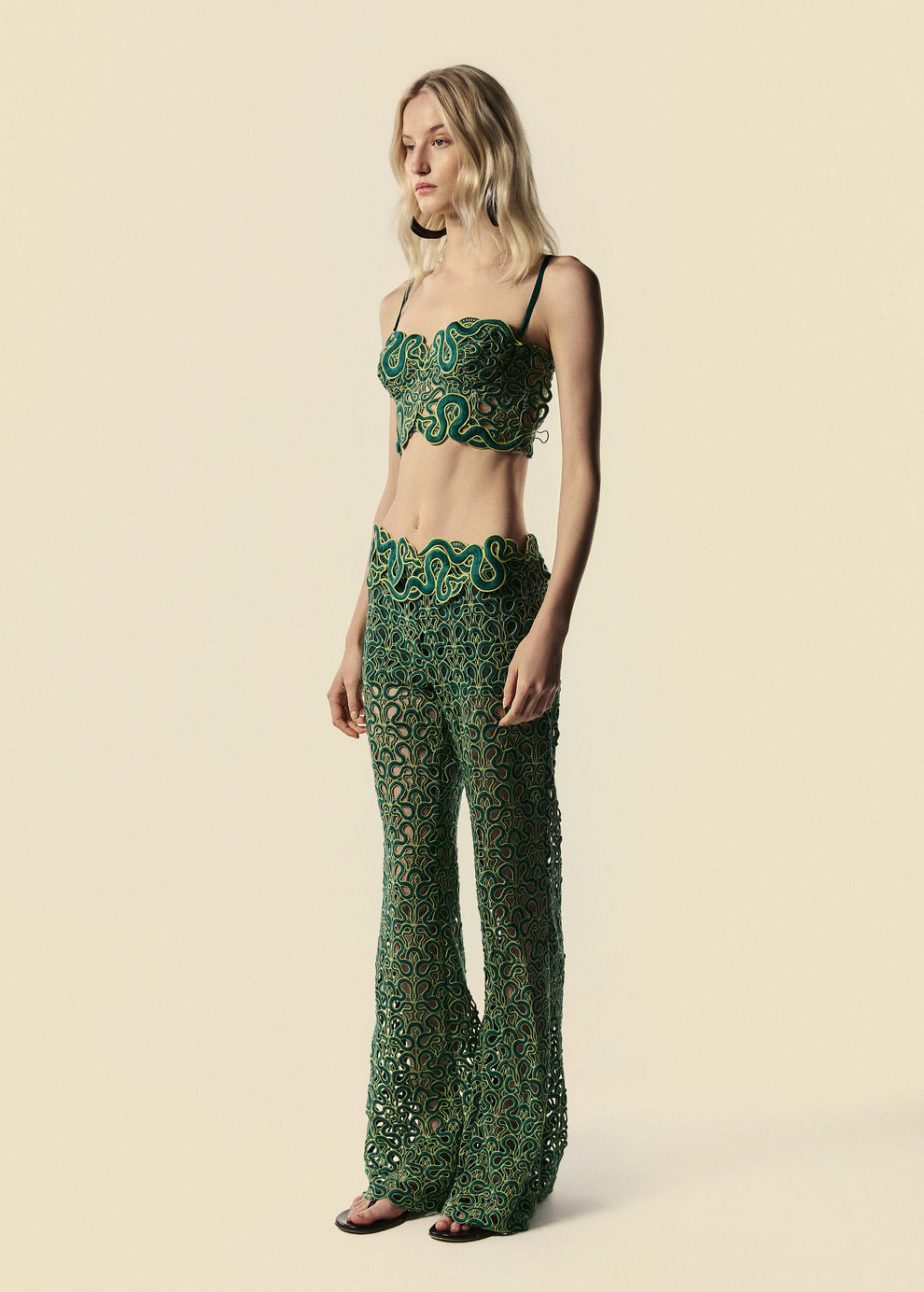 Modelo usa calça flare verde de renda com serpentes e top corset do lançamento de Verão 27 da La Gea.