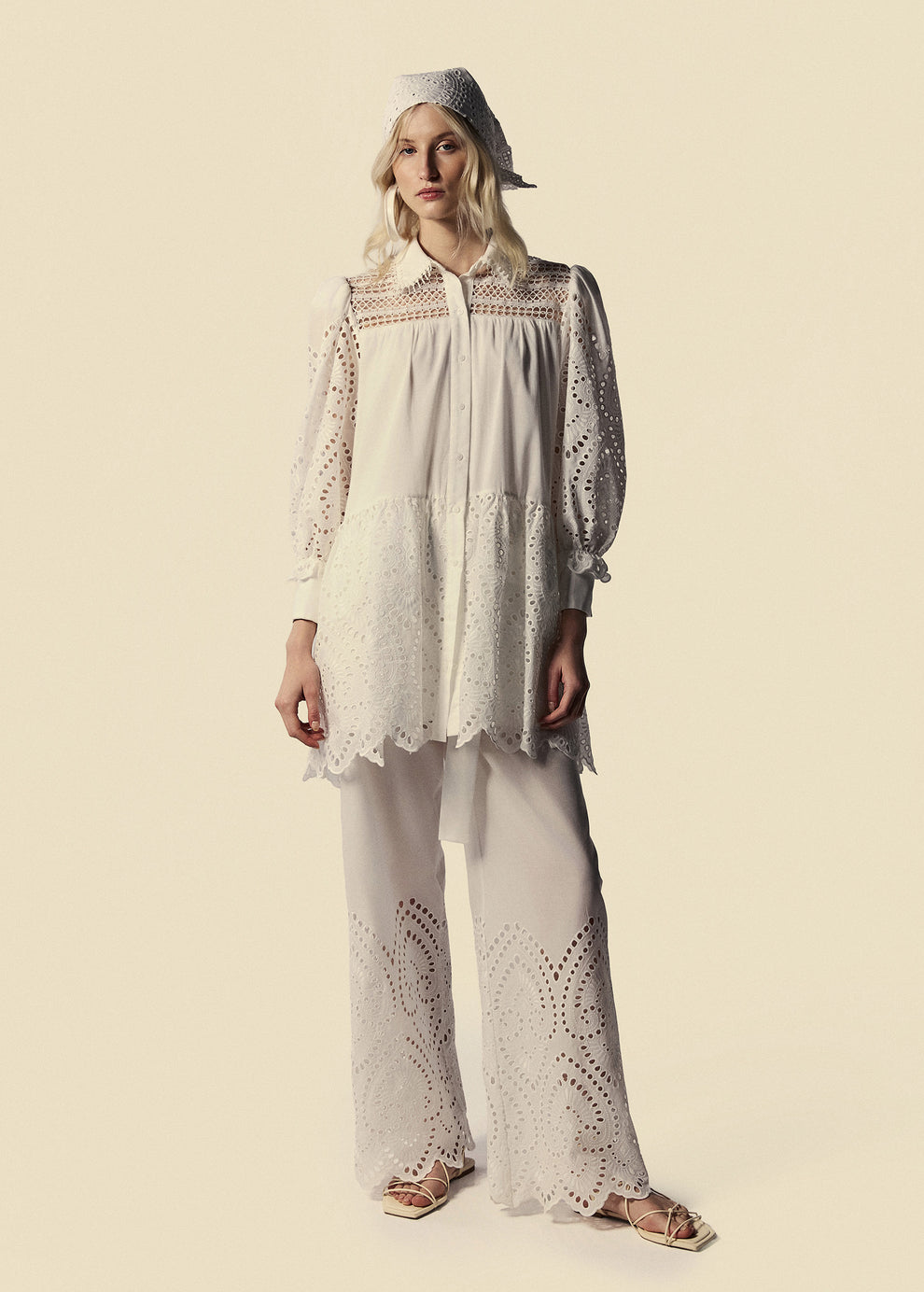 Modelo apresenta visual em laise branco com calça pantalona, chemise e lenço Lumina da La Gea.