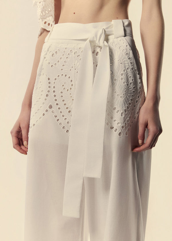 Detalhe da calça pantalona em laise brando com bordados na parte superior da peça e faixa de amarração.