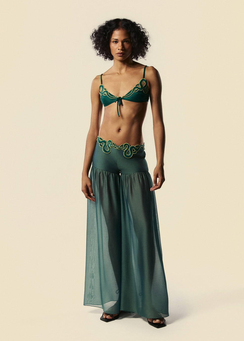 Modelo combina a calça pantalona verde Destino e o top de biquíni Trincas do verão 27 da La Gea com rasteirinha preta de tiras.