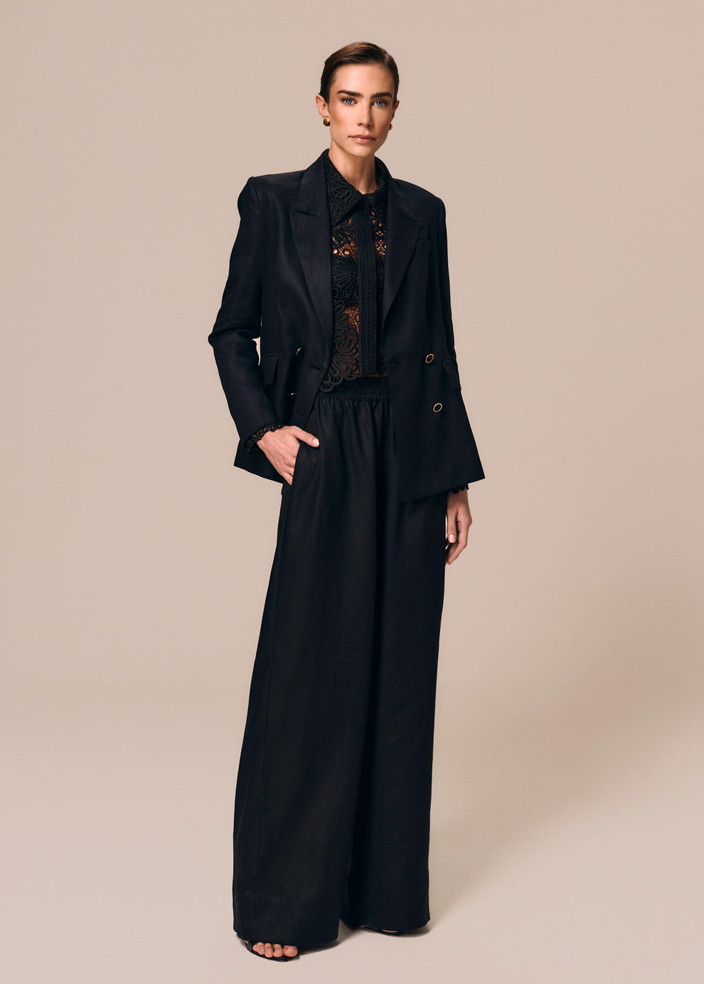 Modelo veste look preto com camisa feminina em renda Cerâmica com blazer alfaiataria e calça reta Essência La Gea