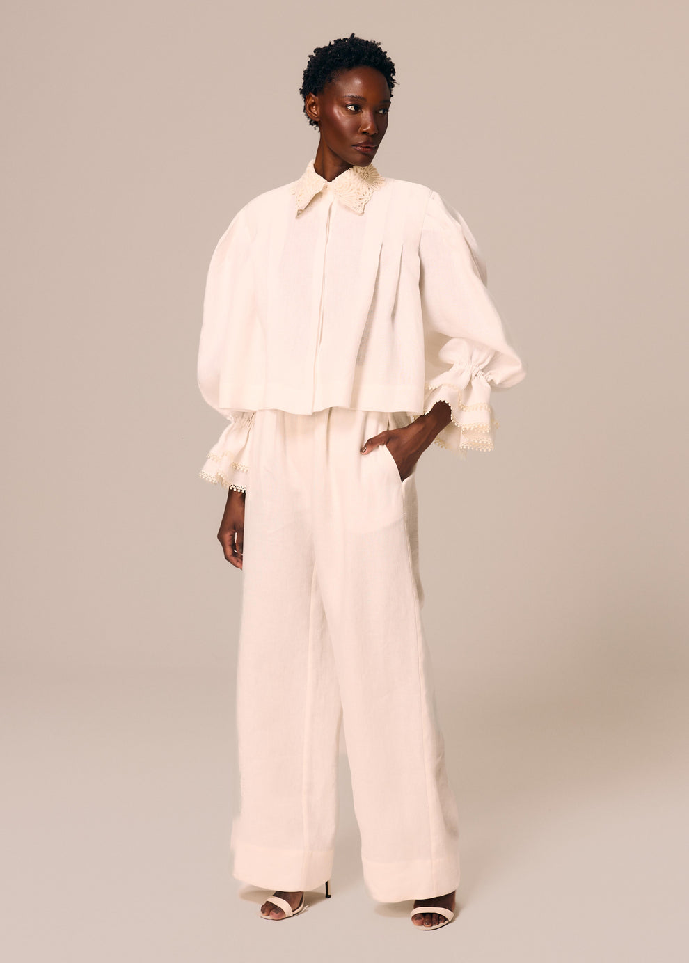 Modelo veste camisa feminina off white Essência com duplo babado no punho e guipir no colarinho e calça boxer reta