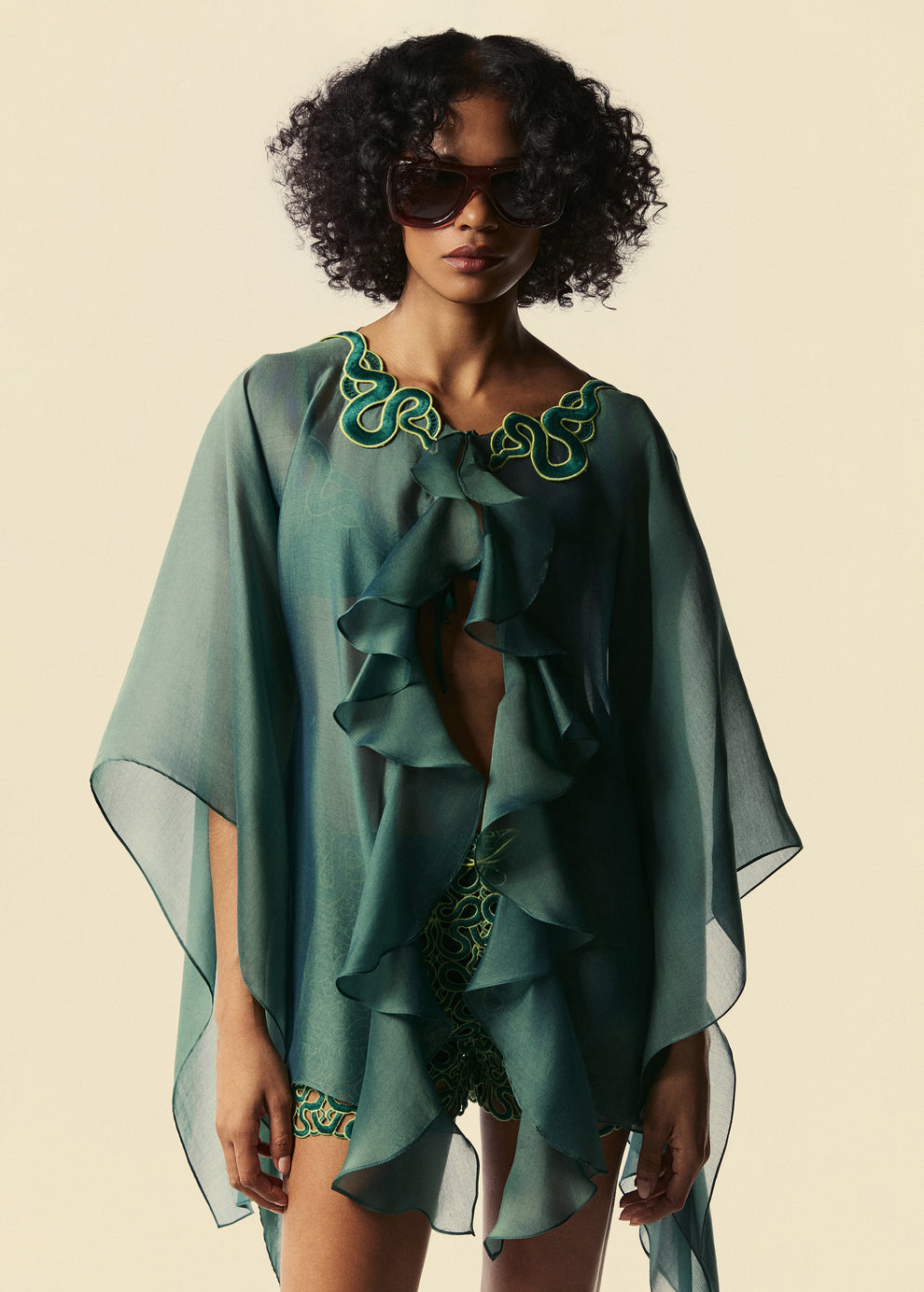 Modelo usa kaftan curto verde com babados Destino com top de biquíni Trincas e shorts curto Trilhas da coleção de Verão 27 da La Gea.