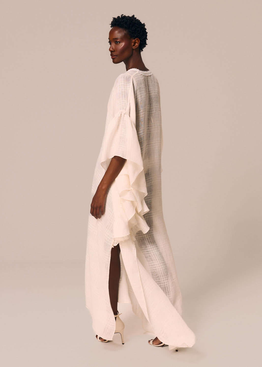 Modelo de costas veste kaftan longo com babados off White Etéreo La Gea com fenda na lateral da barra