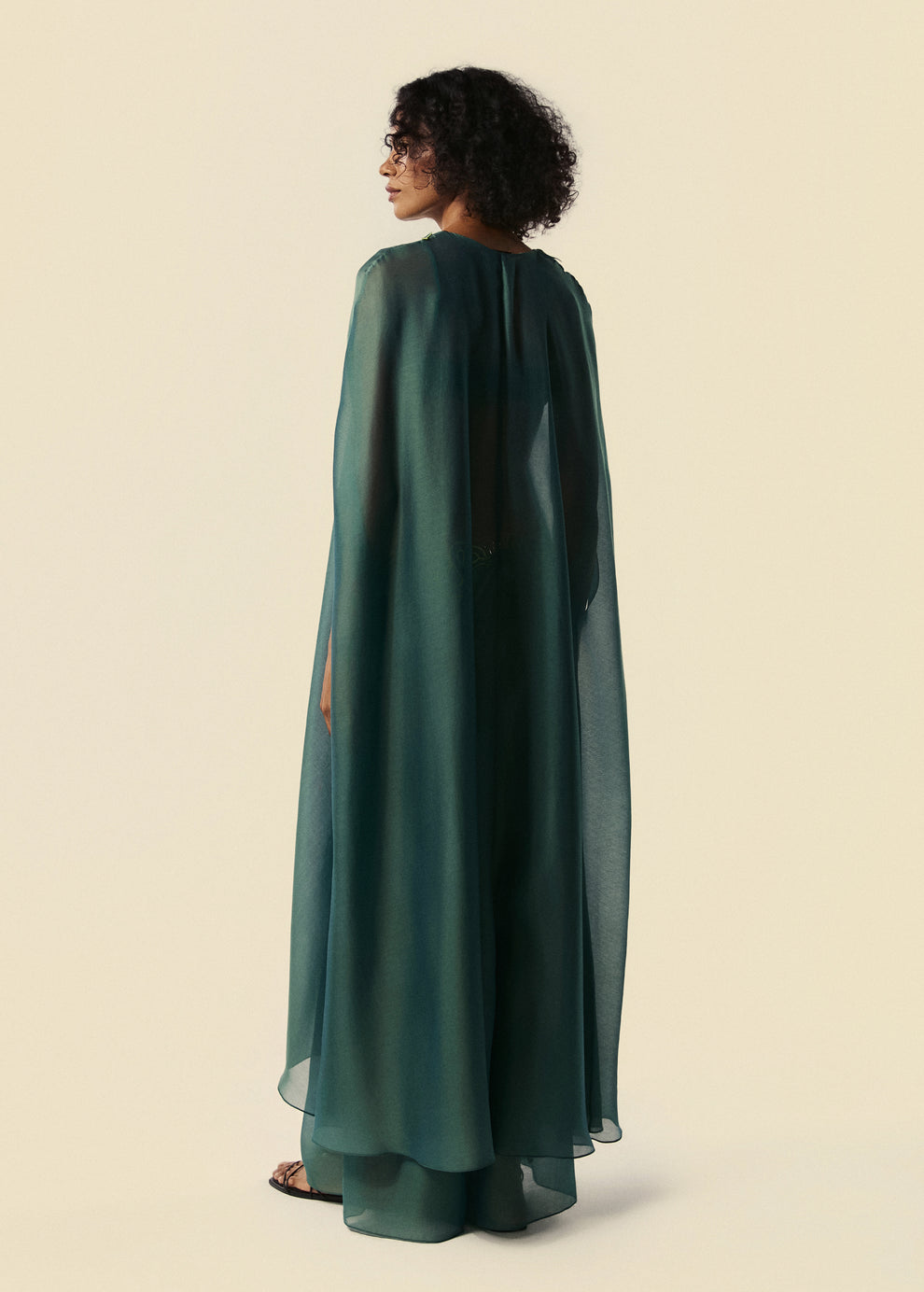 Modelo de costas com kaftan longo verde estilo capa sobreposta da calça pantalona Destino. 