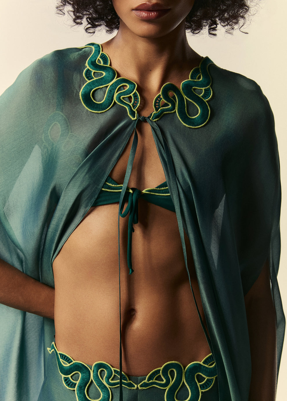 Detalhe da abertura frontal do kaftan longo verde Destino. Sobreposição da calça pantalona e top de biquíni triângulo Trincas.