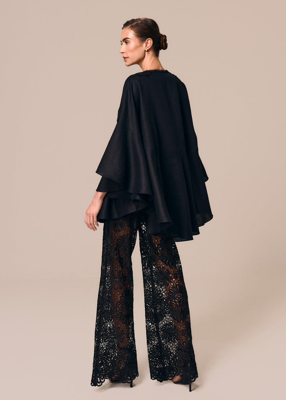Modelo de costas veste look preto com kimono curto Essência La Gea e calça flare em renda Cerâmica