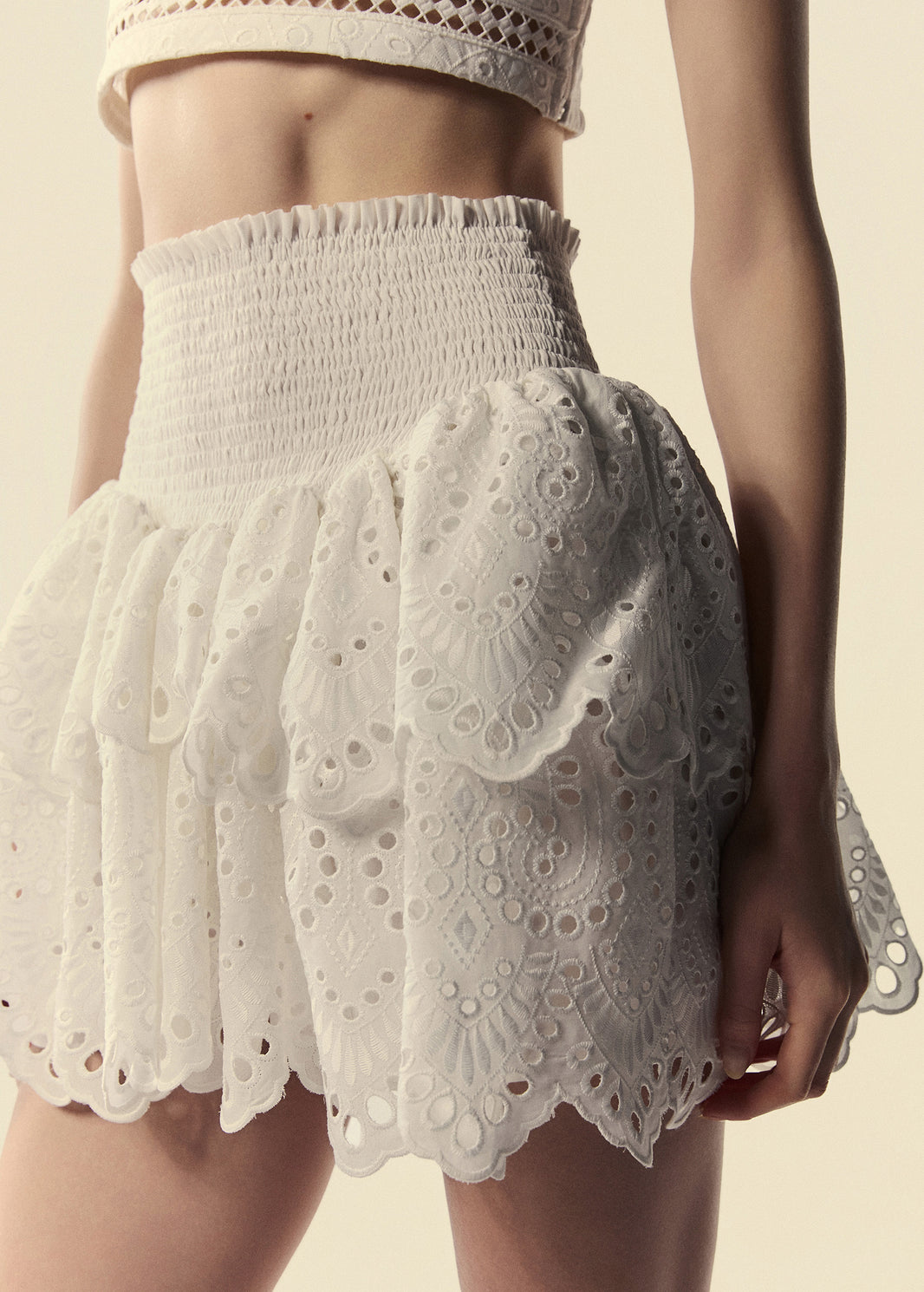 Detalhe da saia curta modelo cintura alta com lastex e babado duplo em laise branco.