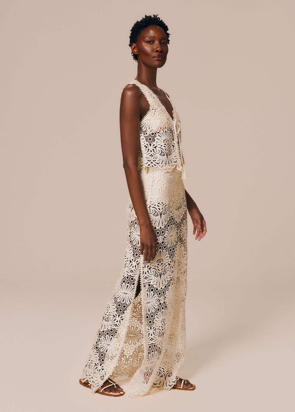 Modelo caminha com look off white de saia longa com fenda em renda Cerâmica La Gea com top de amarração
