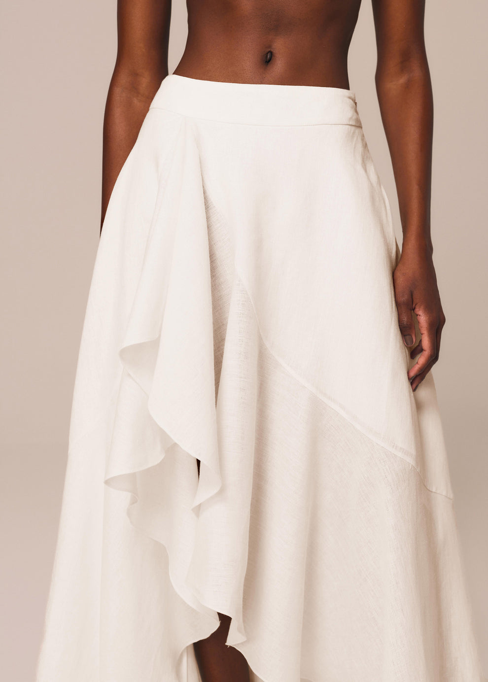 Detalhe da saia longa assimétrica na cor off White Essência La Gea com babado na barra e fenda