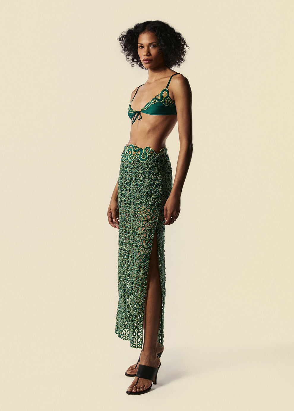 Modelo usa saia longa de renda Trilhas com top de biquíni triângulo Trincas com sandália de salto preto.