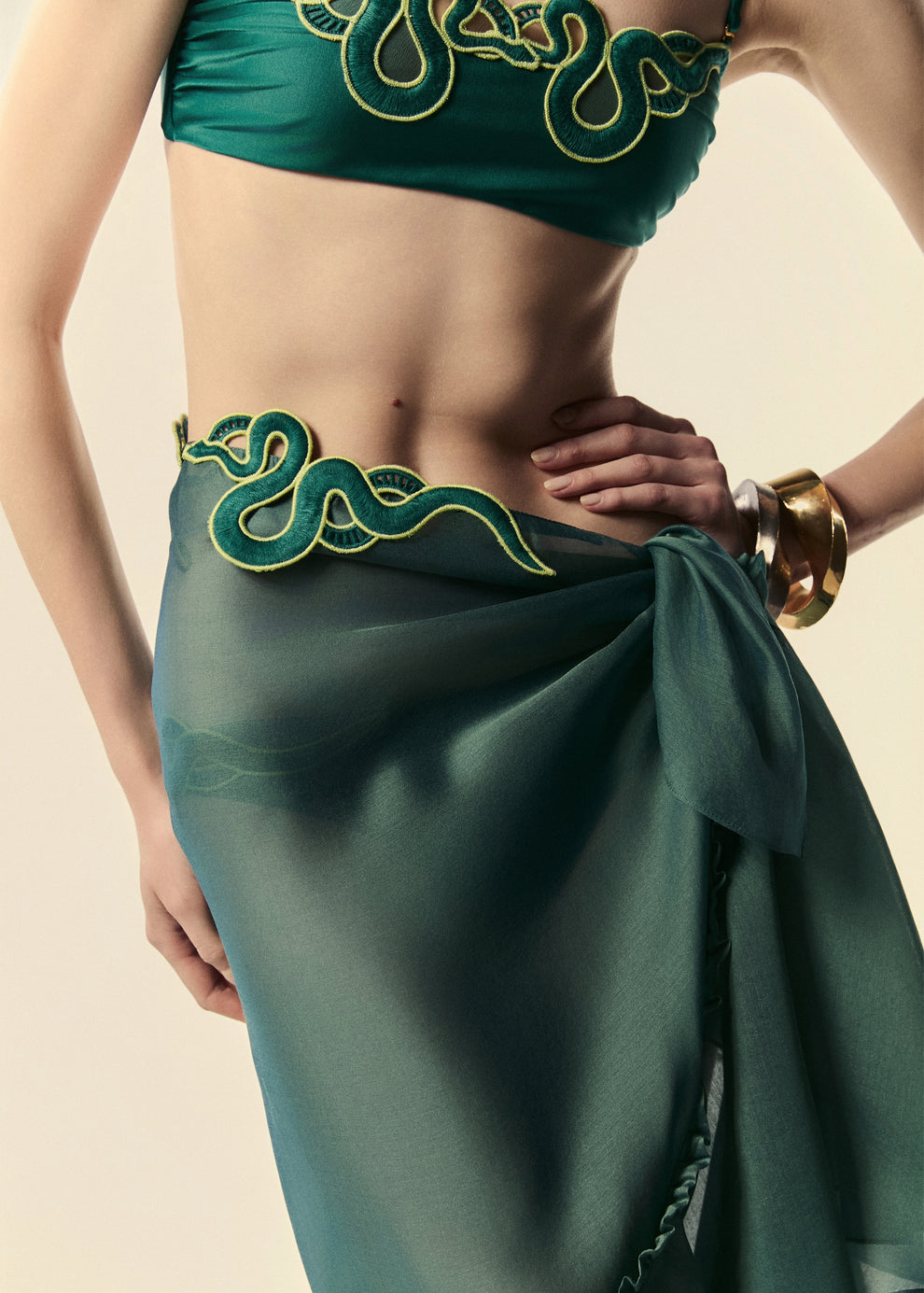Cós da saia pareô verde com amarração lateral e aplicação de guipir de serpente. 
