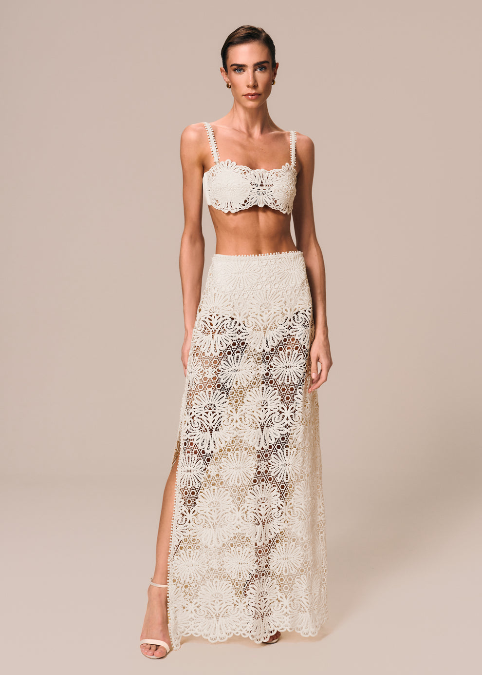 Modelo veste composição de look off White com top de biquíni bandeau Pedra e saia longa com hot pants Cerâmica La Gea