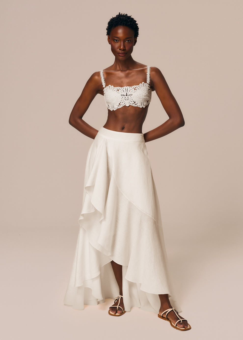 Modelo veste look off White com top de biquíni bandeau Pedra e saia longa assimétrica com babado Essência La Gea