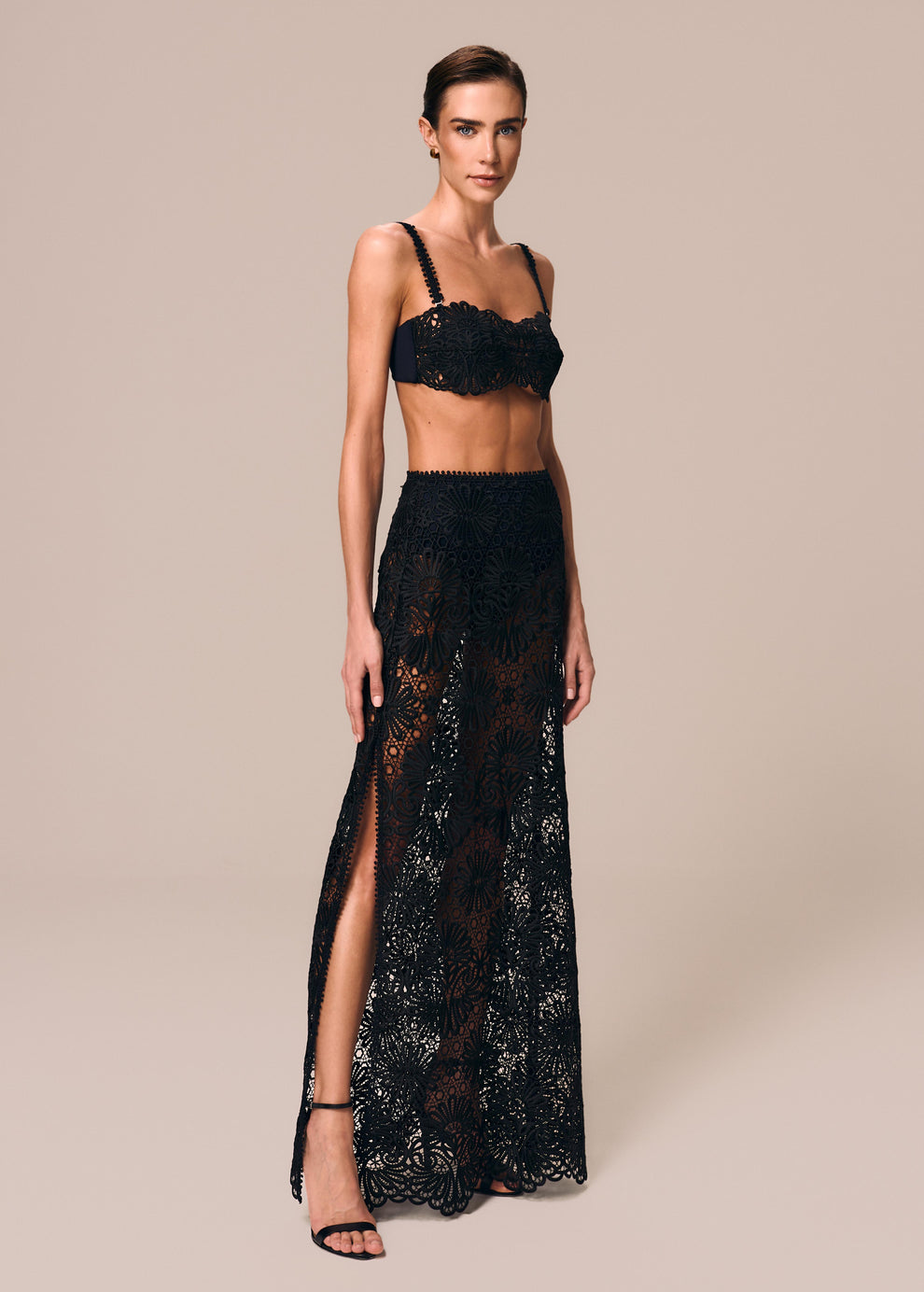 Modelo veste composição na cor preta top de biquíni bandeau Pedra com saia longa de renda e hot pants Cerâmica La Gea 