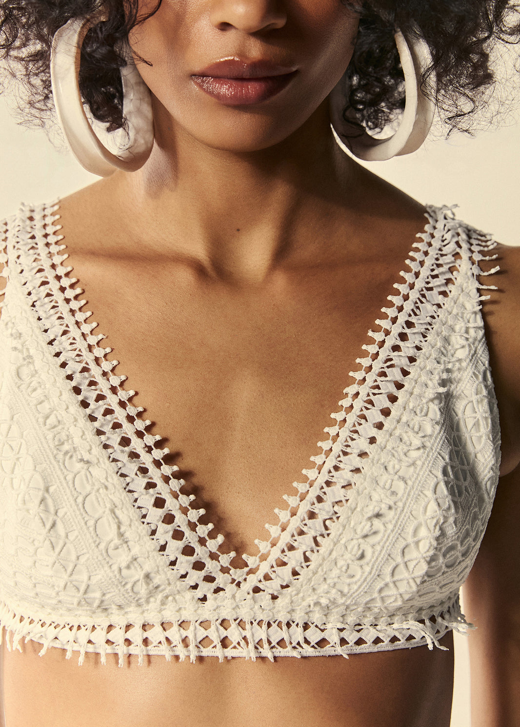 Detalhe do decote do top de biquíni triângulo branco com guipir da coleção de Preview Verão 27. 