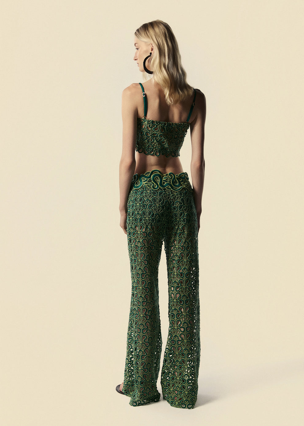 Modelo de costas com o top corset e calça flare esverdeadas com serpentes da coleção de Verão da La Gea.