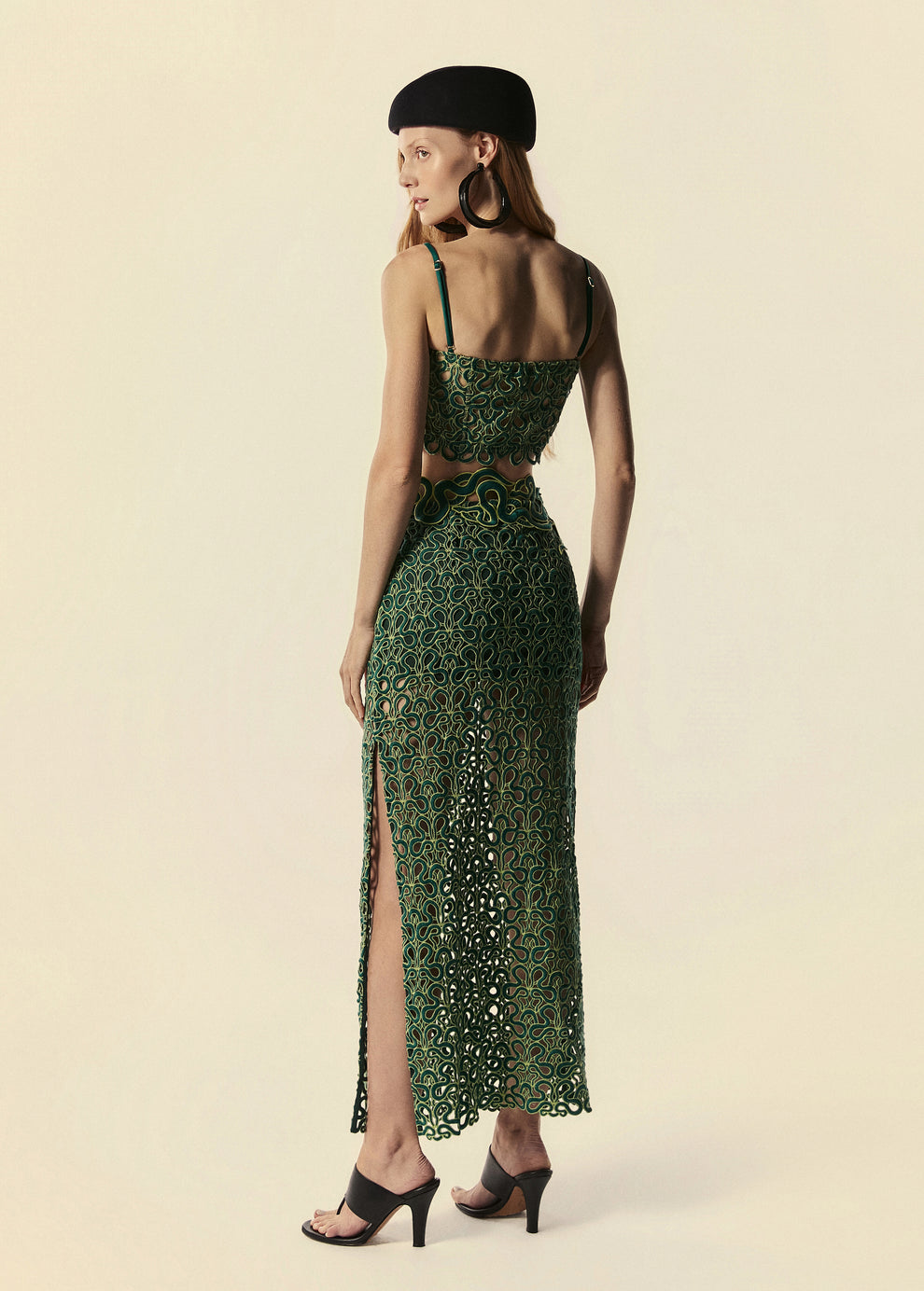 Modelo de costas com o top corset e saia longa com detalhes em serpentes esverdeadas.