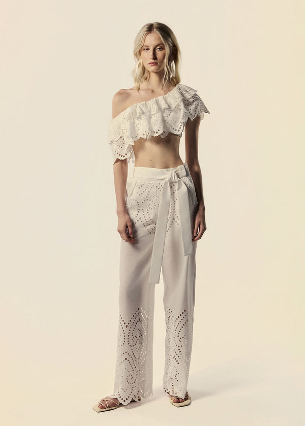Modelo combina o top de um ombro só branco La Gea com calça pantalona em laise de algodão.