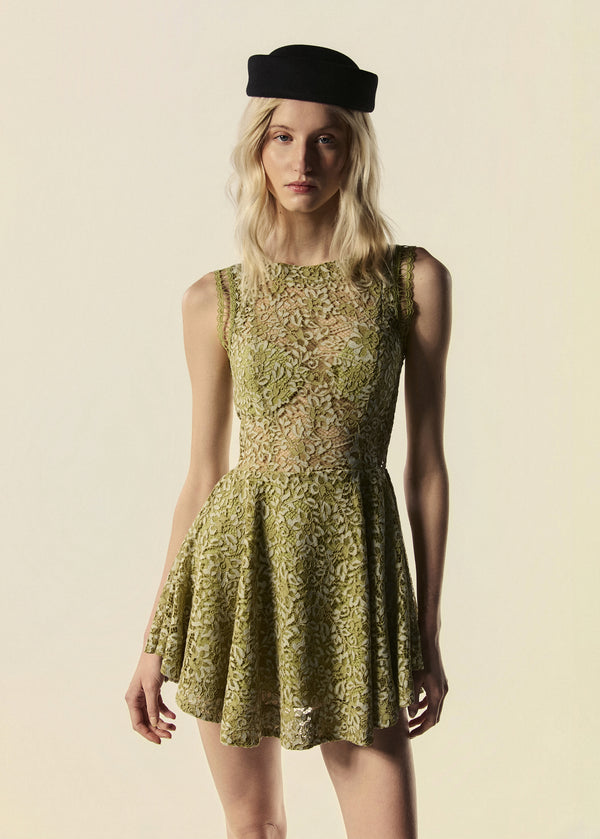 Modelo usa vestido curto verde Bosque em renda com chapéu preto.