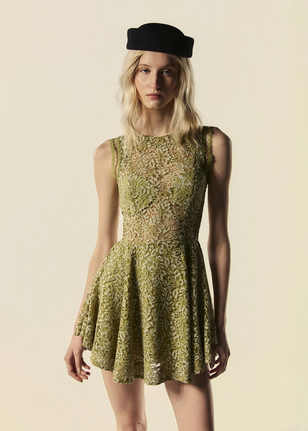 Modelo usa vestido curto verde Bosque em renda com chapéu preto.