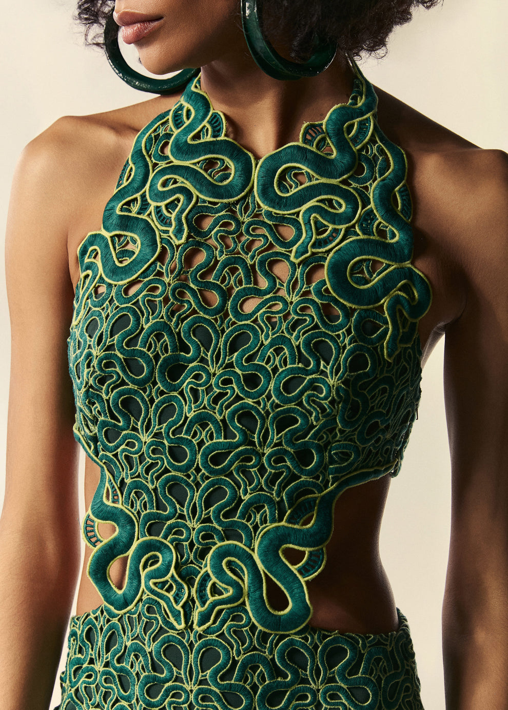 Detalhe da renda do vestido curto Trilhas com recortes laterais e desenhos de serpentes no comprimento.