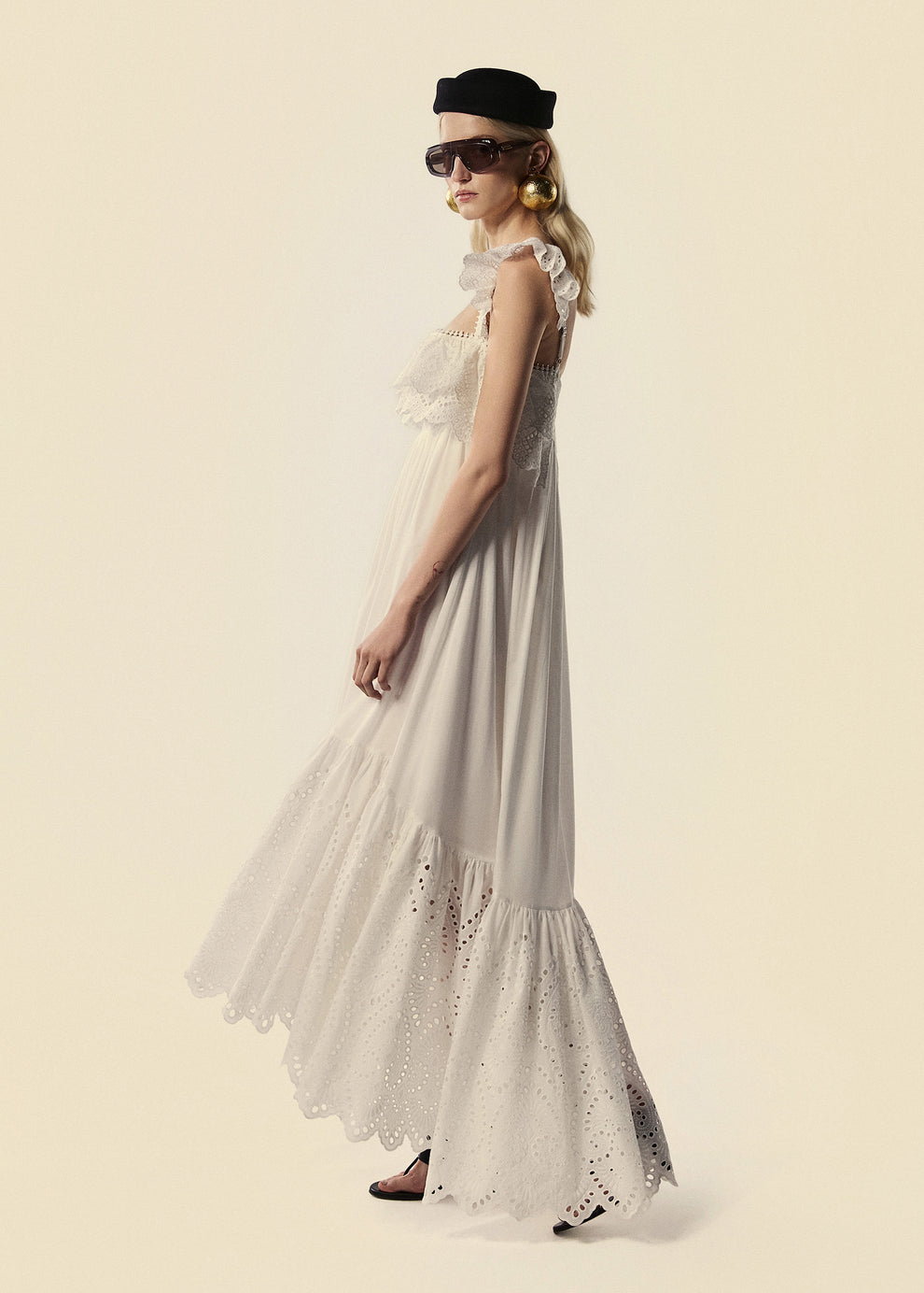 Modelo caminha com o vestido longo Lumina com babados em laise branco.