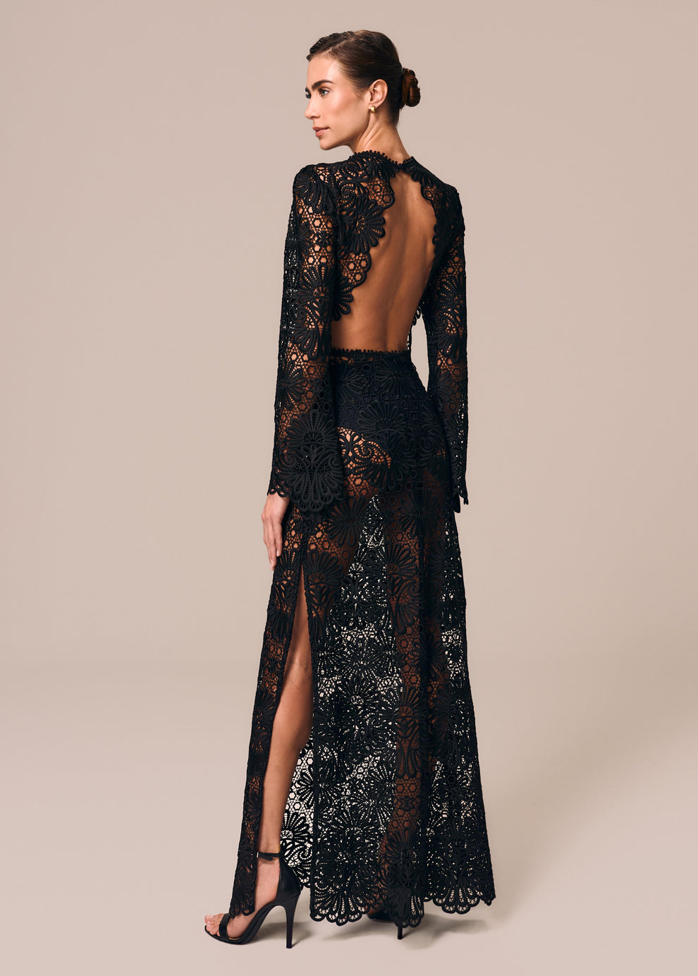 Modelo de costas usa vestido longo em renda com manga longa flare preto Cerâmica La Gea