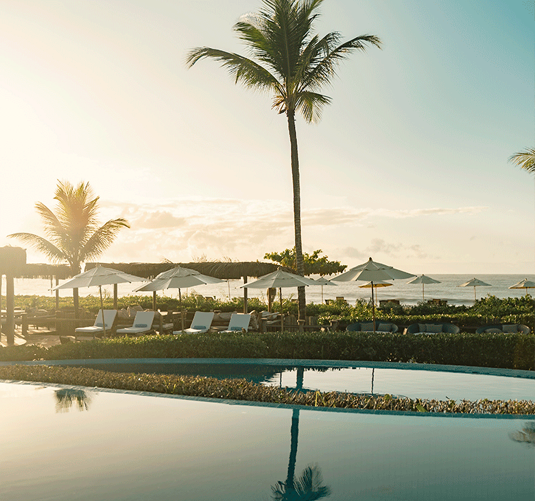 Imagem Estrela d’ Agua Hotel com piscina à frente com espreguiçadeira e pé de coqueiro.