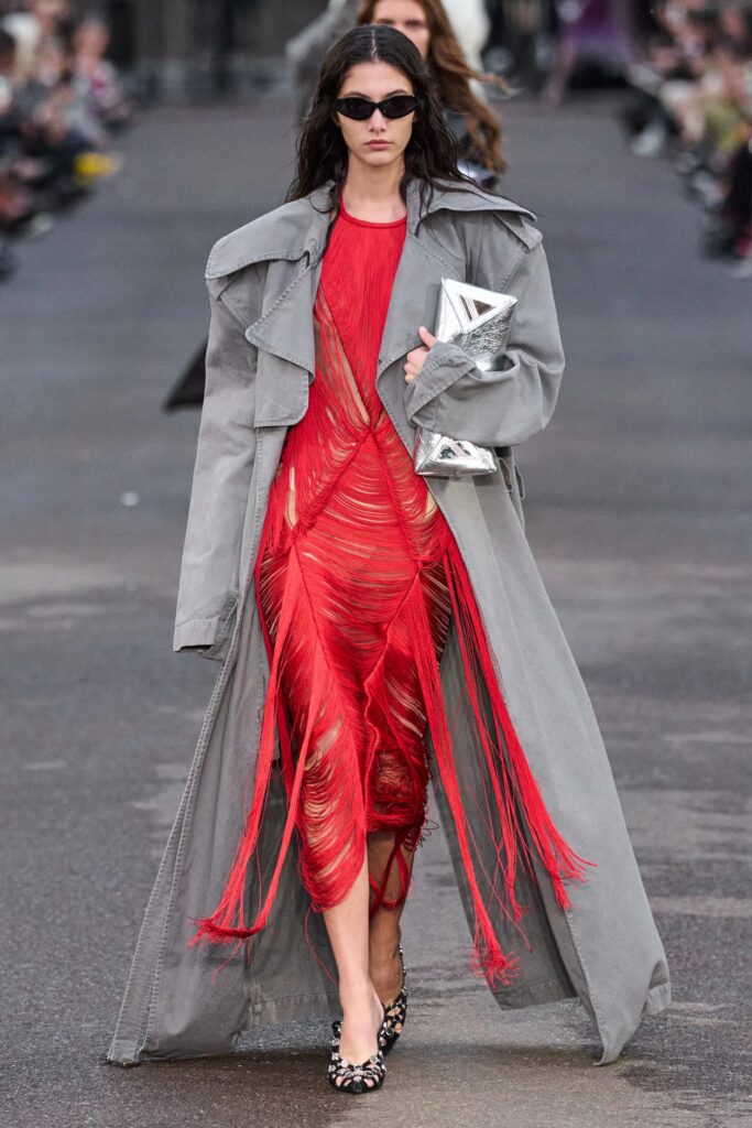Modelo desfila coleção Bottega, vestido vermelho com sobretudo cinza